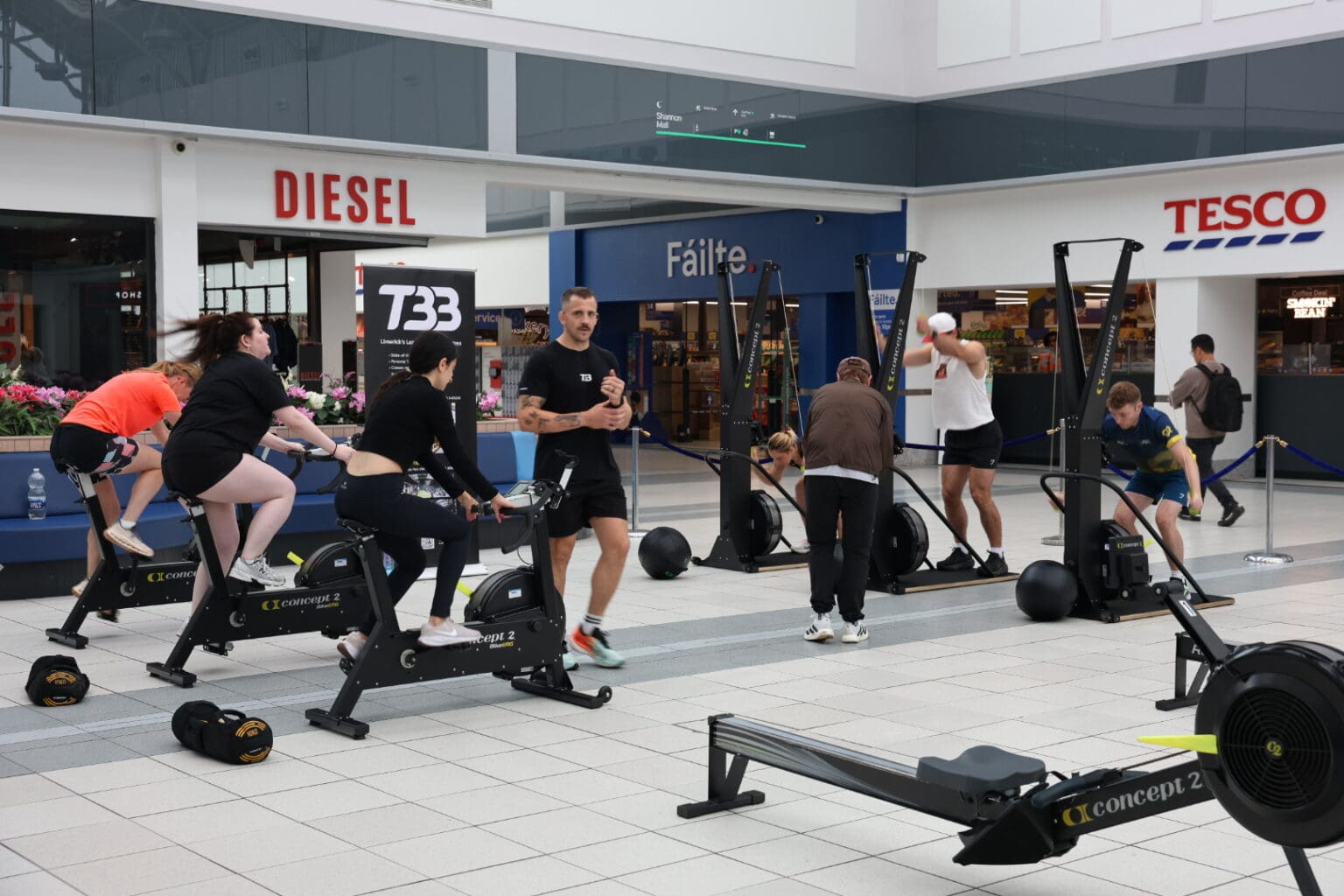 Exercise bikes, rowers and ski ergs set up on the mall floor at Crescent Shopping Centre in front of Diesel.